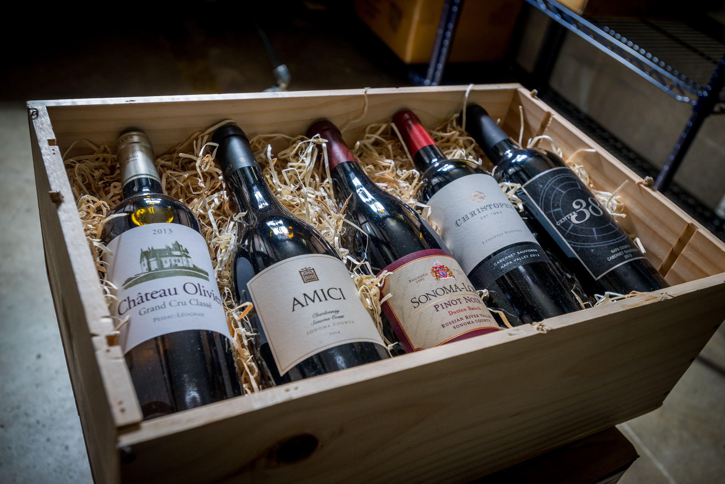 A wooden crate of premium wine bottles packed in straw for secure shipping and storage
