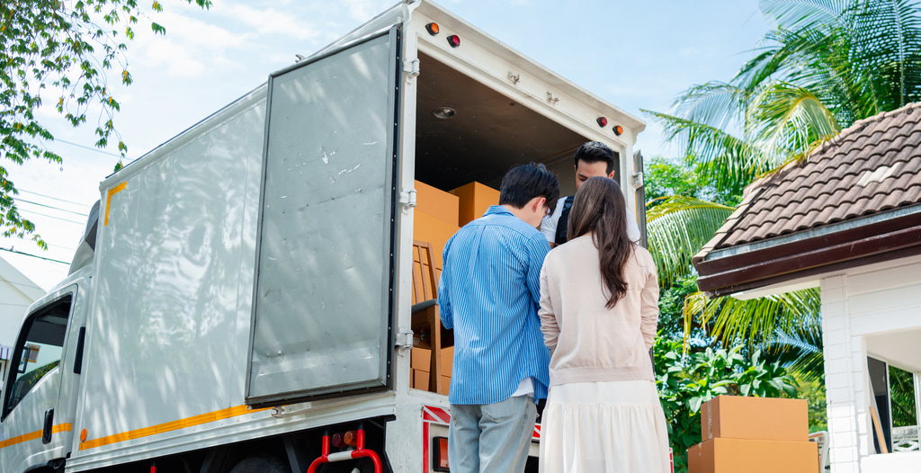 Young couple standing by a moving truck filled with boxes during a home relocation
