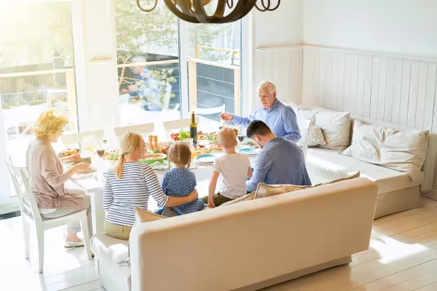 Multi-generational family enjoying a meal together in a bright, modern dining room after a successful home relocation