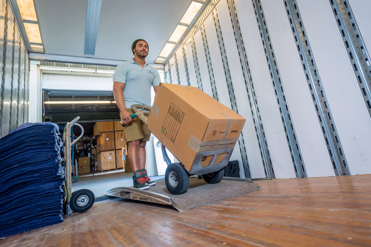 Professional logistics team carefully loading a variety of wrapped furniture and household items into a moving truck for a residential relocation
