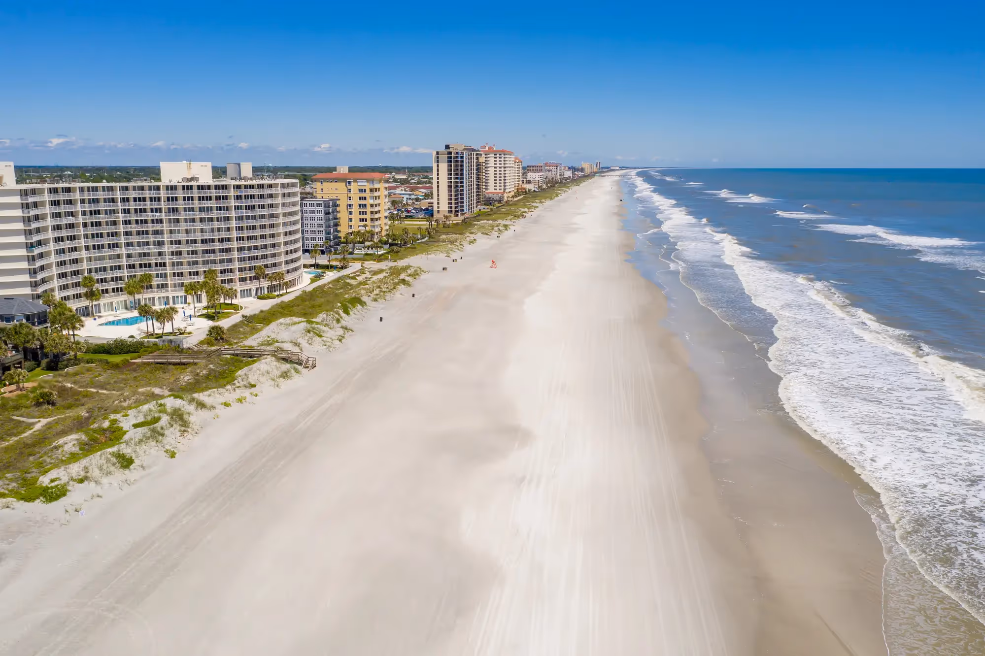 Aerial view of wide sandy beaches and oceanfront high-rise buildings in Jacksonville Beach, Florida