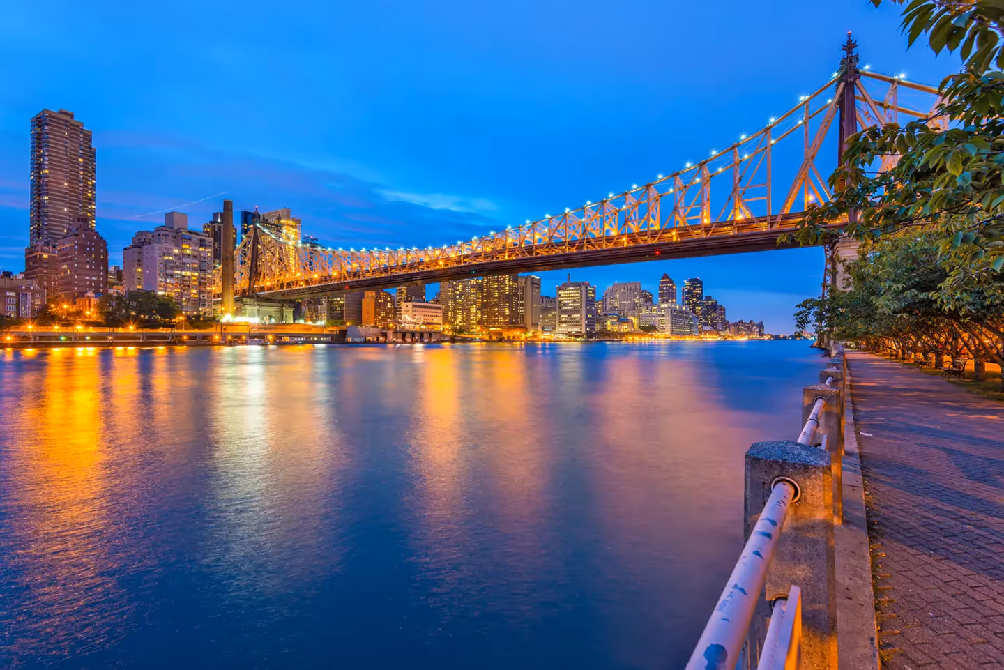 Illuminated Ed Koch Queensboro Bridge spanning the East River at twilight with the New York City skyline