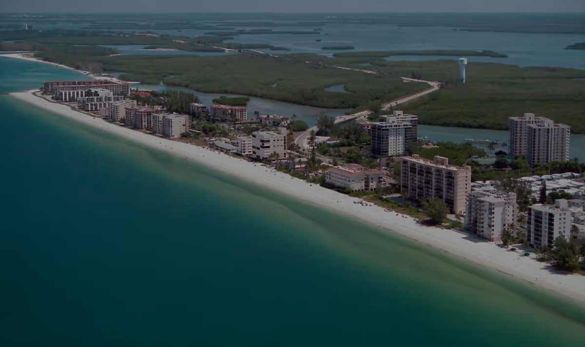 Aerial view of a coastal resort area in Bonita Springs, Florida, featuring luxury high-rise buildings and tropical greenery