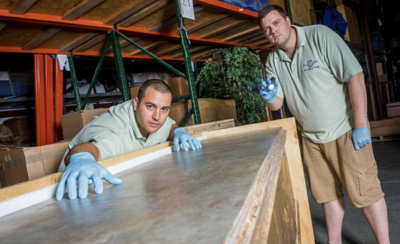 Professional movers in gloves inspecting furniture for safe storage and transport