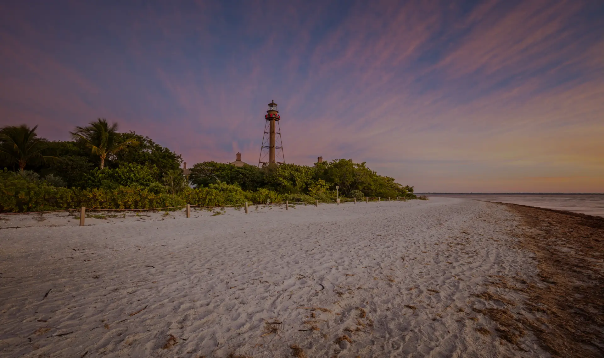 Aerial view of the Sanibel Island coastline featuring white sandy beaches, lush greenery, and turquoise Gulf waters in Florida
