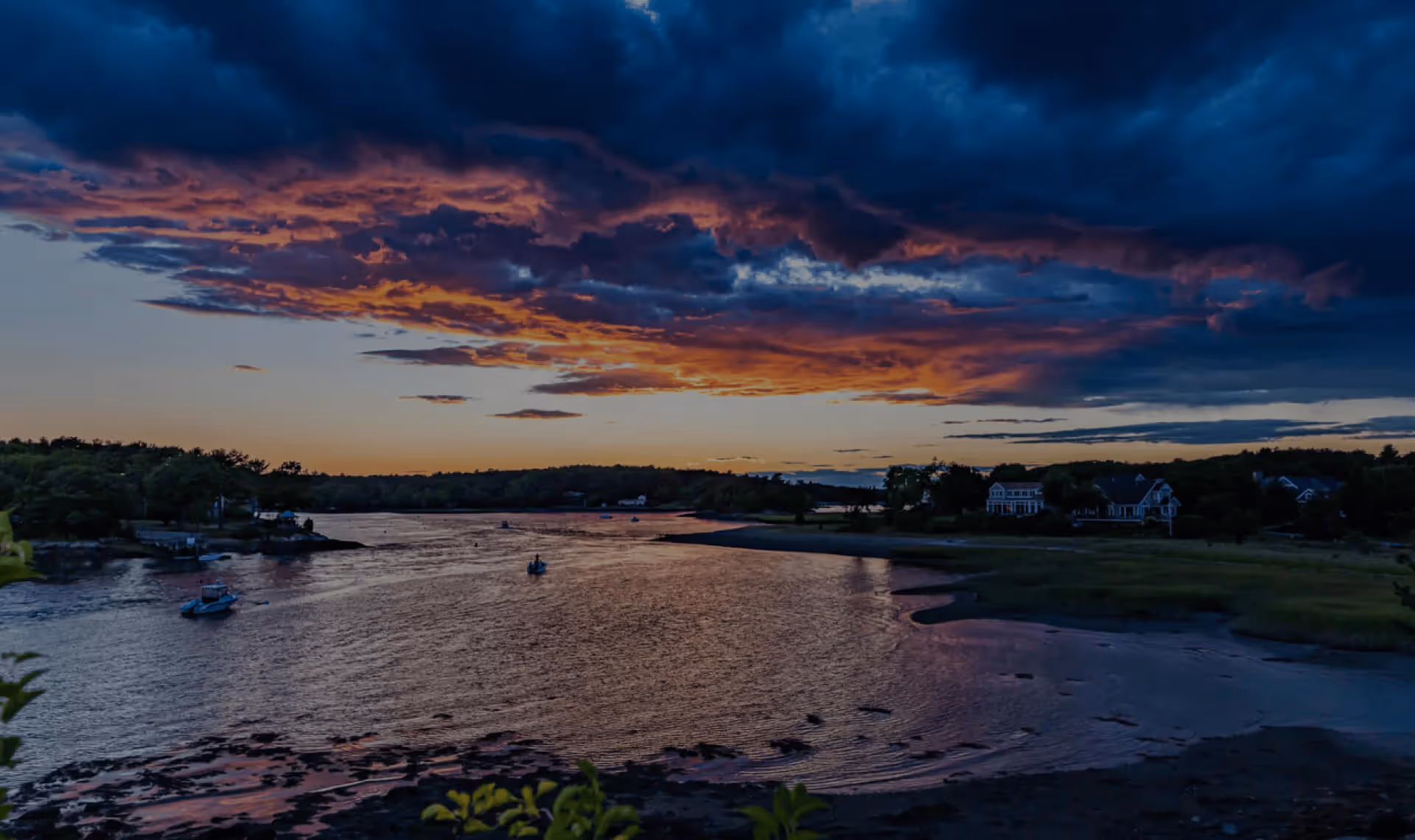 A sunset over a river with houses and trees