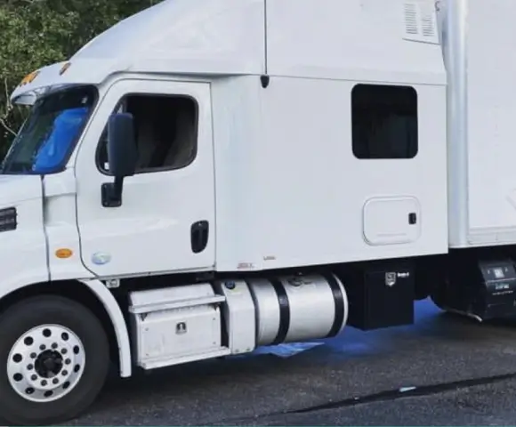 White Freightliner semi-truck with sleeper cab and side fuel tanks