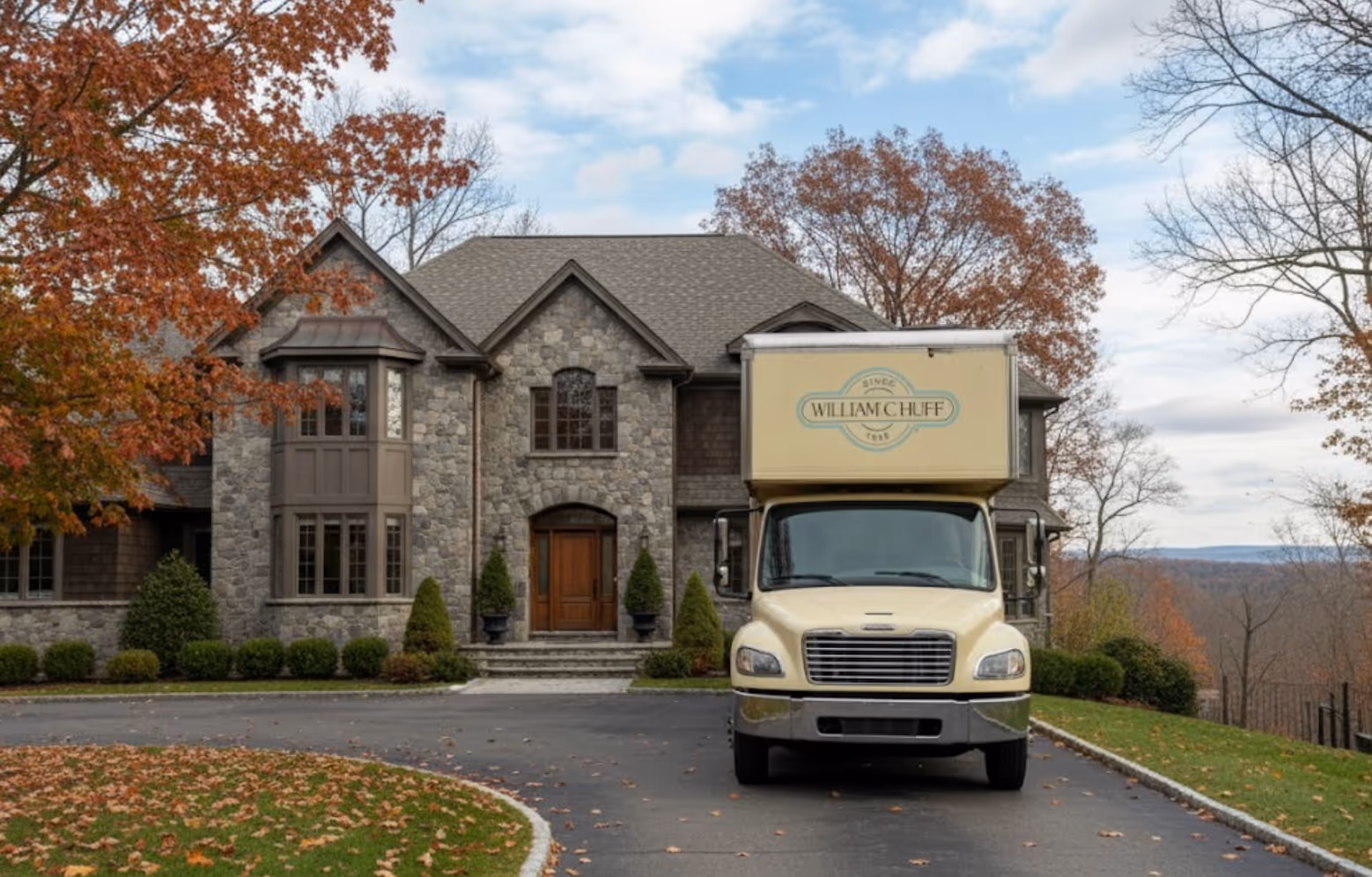 William C. Huff moving truck parked in front of a modern luxury estate with a large driveway and manicured landscaping