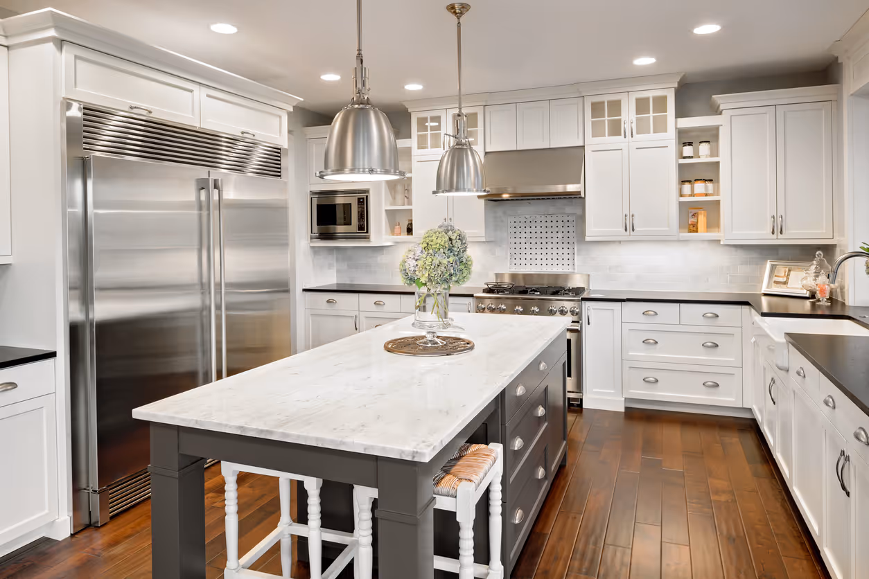 Modern kitchen with white cabinetry, a marble-top island, and stainless steel appliances