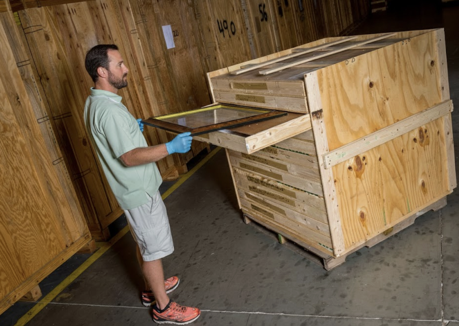 A professional William C. Huff art handler carefully unpacking a large, high-value painting for a gallery installation