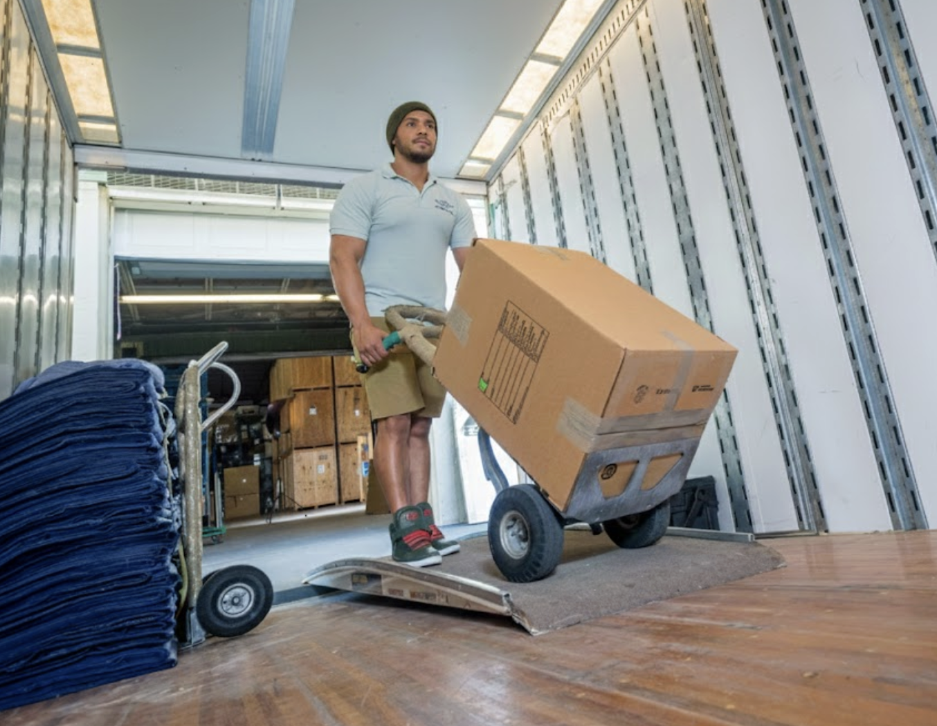 Two professional movers loading a William C. Huff truck with protective-wrapped furniture for a residential relocation