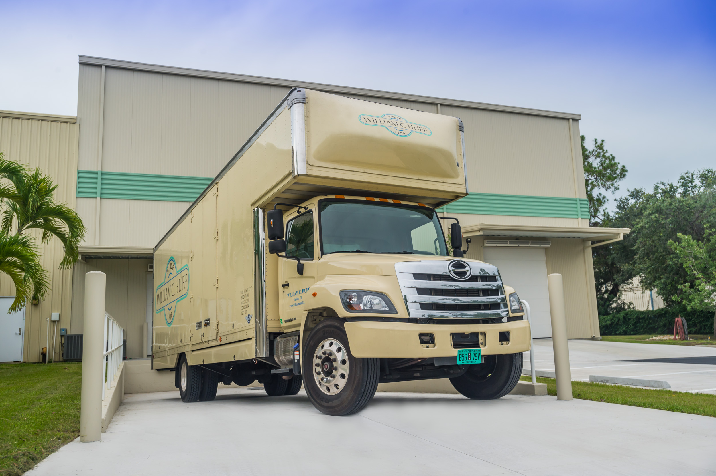 A William C. Huff moving truck parked in front of a modern climate-controlled storage facility in Naples