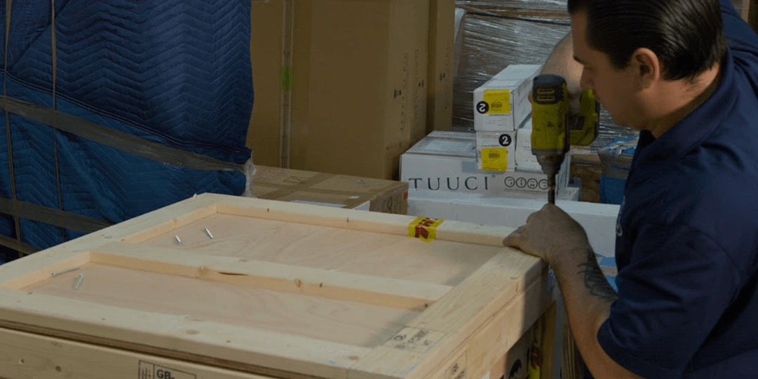 William C. Huff craftsman fastening a custom wooden crate with a power drill