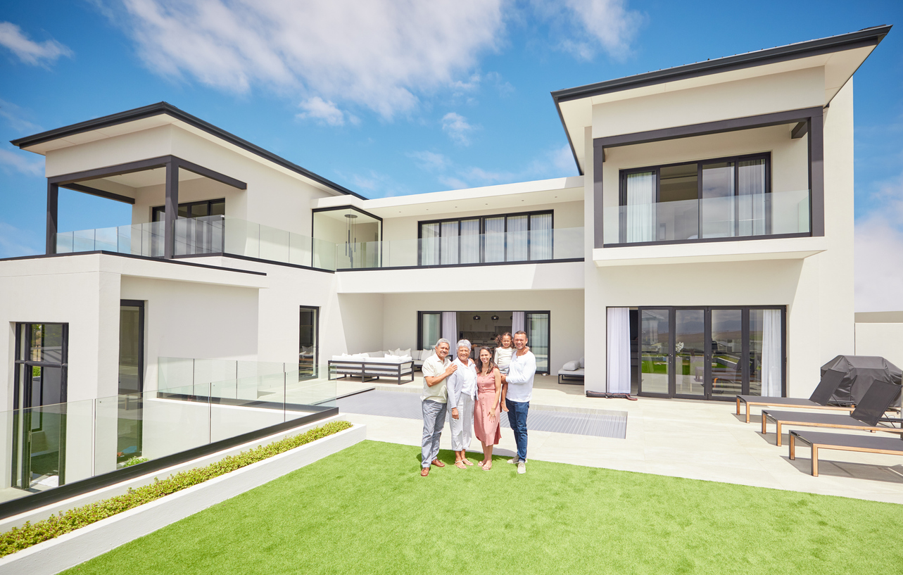 A multi-generational family standing together on the lawn of a modern luxury estate
