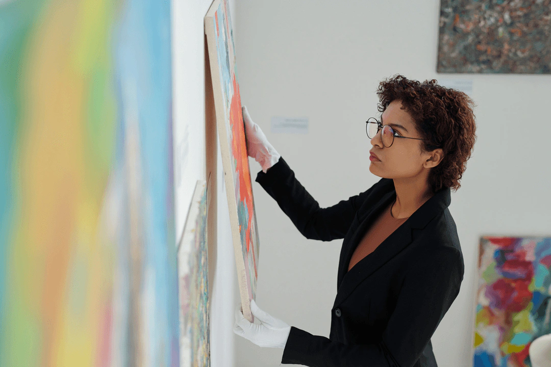 Art professional hanging an abstract painting on a white wall