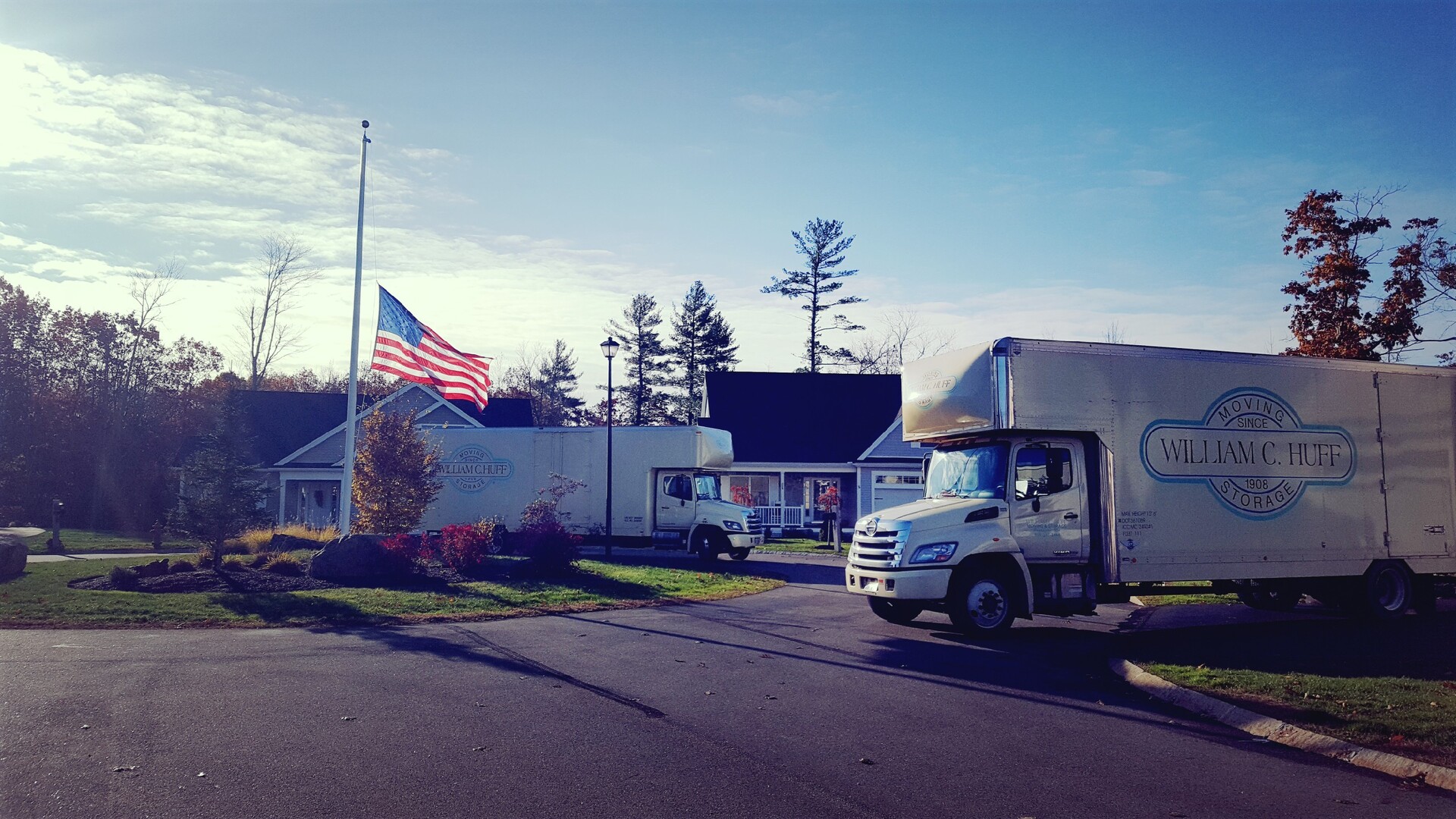 William C. Huff moving trucks parked in a residential driveway with an American flag.