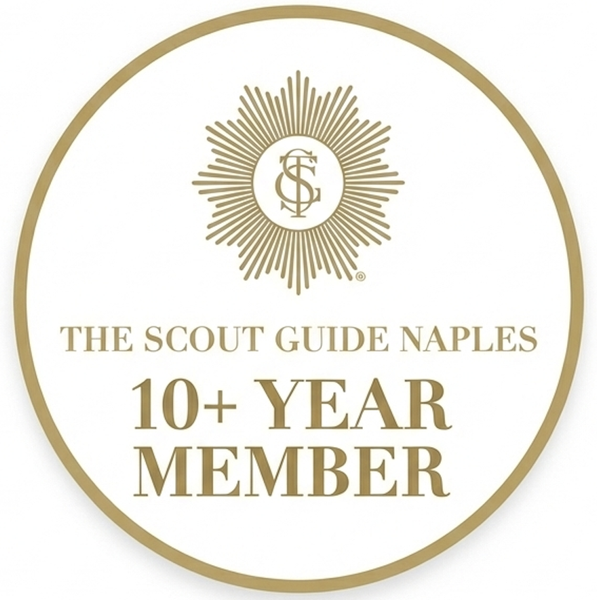 A circular gold and white membership badge, featuring a prominent sunburst design with an intertwining 'TCG' monogram logo inside. The badge includes gold serif text below the logo, reading: "THE SCOUT GUIDE NAPLES," with "10+ YEAR" and "MEMBER" in large text below.