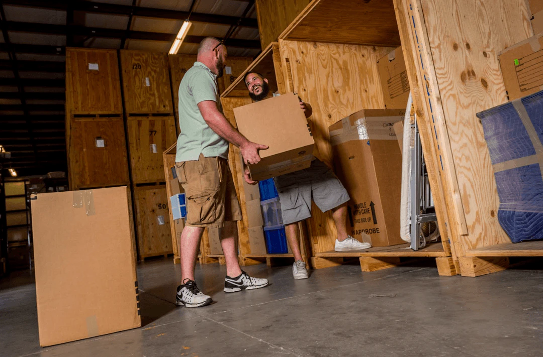 Two William C. Huff movers loading boxes into a wooden storage vault
