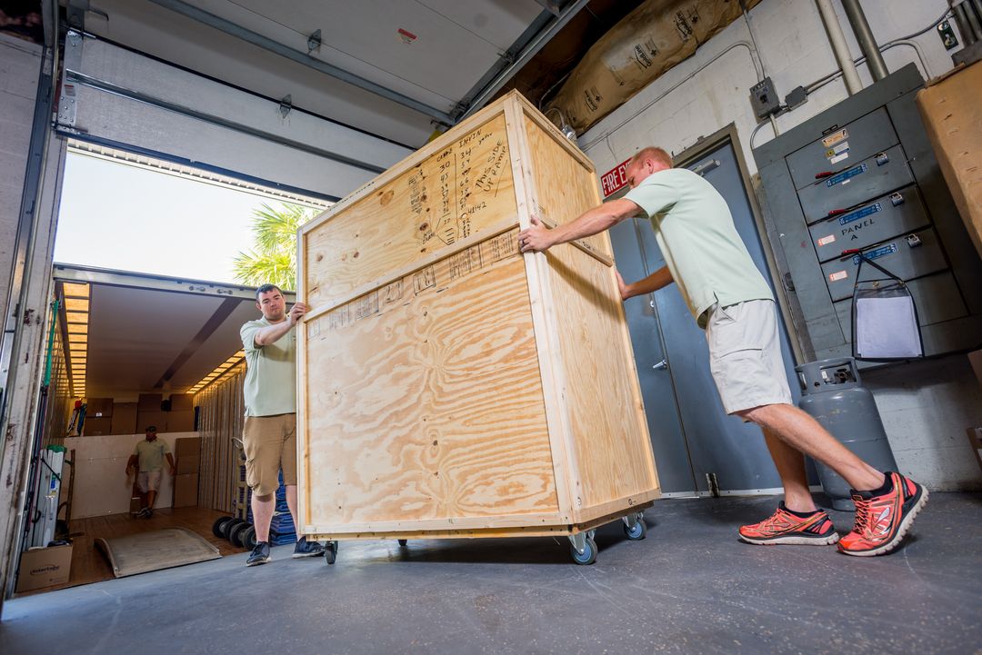 William C. Huff mover guiding a large wooden crate onto a truck lift gate